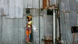 A woman holding a baby looks out of a window from a shanty in Dharavi, Mumbai, India, October 15, 2009, photo by Arko Datta/Reuters
