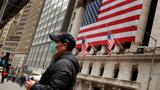 A man wears a mask while walking past the New York Stock Exchange in New York City, March 17, 2020, photo by Lucas Jackson/Reuters