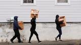 Residents carry boxes of free groceries distributed at a pop-up food pantry by the Massachusetts Army National Guard in Chelsea, Massachusetts, April 24, 2020, photo by Brian Snyder/Reuters