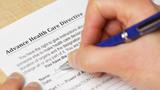 A person filling out a form titled Advance Health Care Directive and a pen, photo by PictureLake/Getty Images