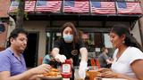 As phase one of reopening begins in Northern Virginia, a waitress with a face mask serves diners at a restaurant in Alexandria, Virginia, May 29, 2020, photo by Kevin Lamarque/Reuters
