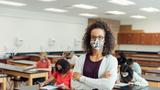 High school teacher in classroom with students wearing face masks, photo by RichVintage/Getty Images