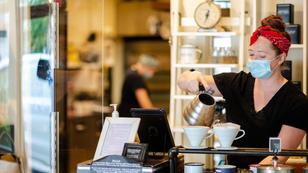 A barista making coffee while wearing a mask, photo by stockstudioX/Getty Images