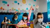 Elementary schoolchildren wearing face masks in a classroom, photo by kevajefimija/Getty Images