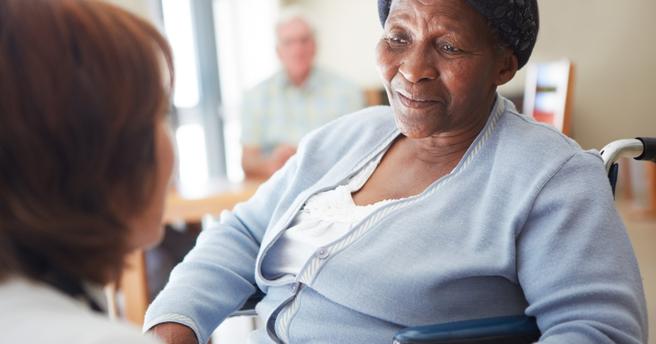 Elderly woman in a wheelchair looking at her caregiver, photo by Squaredpixels/Getty Images