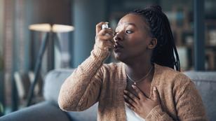 A woman using an inhaler and holding her chest, photo by PeopleImages/Getty Images