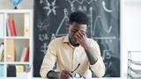 A tired or stressed teacher at his desk, photo by shironosov/Getty Images