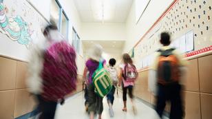 Elementary students with backpacks walking in a school hallway, photo by Thomas Barwick/Getty Images