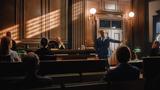A male public defender presents his case in a wood-paneled courtroom. Photo by Gorodenkoff/Adobe Stock