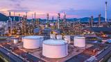 Aerial view of oil and gas chemical tanks with an oil refinery plant in the background 