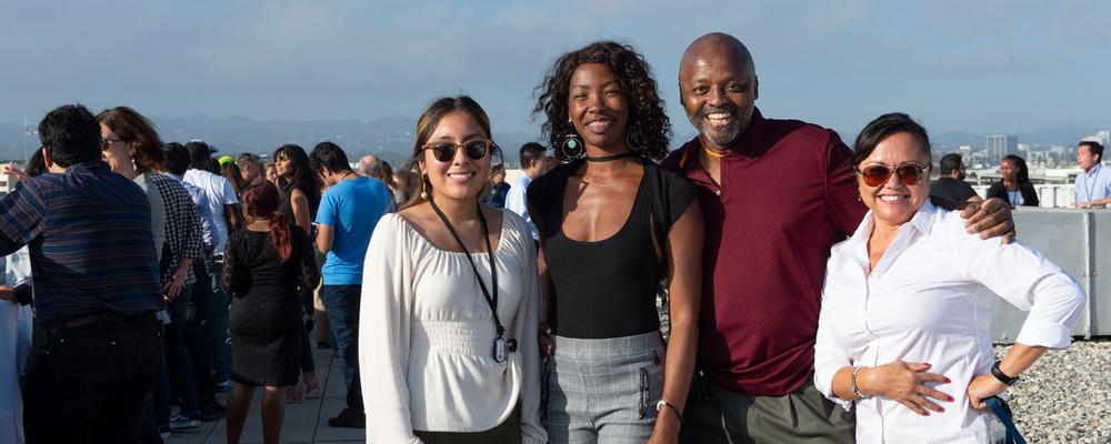 Photo of four RAND employees posing together at a celebration on the roof of the Santa Monica Headquarters.