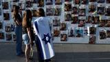 Israeli women, one covered with an Israeli flag, stand in front of a wall of photos of Israelis held hostage by Hamas in Gaza in Tel Aviv, Israel, November 03, 2023, photo by Gili Yaari/NurPhoto/Reuters