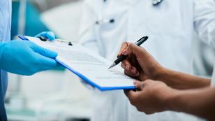 Close-up of a woman signing paperwork during a medical appointment, photo by Drazen Zigic/Getty Images
