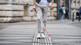 Midsection of young blind man with white cane walking across the street in city, photo by Halfpoint /Adobe Stock