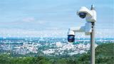 Cameras at the top of a hill with a city in the distance with a web of surveillance over it, photo by Iryna Dobytchina/Getty Images