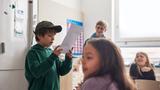 Boy reading in front of class, photo by Johnér/Adobe Stock