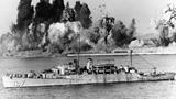 USS Begor (APD-127) stands offshore, ready to embark the last U.N. landing craft, as demolition charges wreck Hungnam's port facilities, 24 December 1950, photo by U.S. Navy.