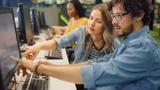A man and a woman working together at a computer in a lab or library, photo by Gorodenkoff/Adobe Stock