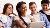 A teenage girl and her friends watch a video on a tablet, photo by Prostock-studio/Adobe Stock
