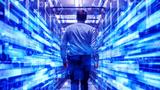 IT specialist walking through data center full of rack servers and supercomputers, photo by Gorodenkoff/Adobe Stock
