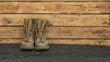 Combat boots against a wooden backdrop, photo by serikbaib/Adobe Stock