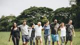 A diverse group of people walking arm-in-arm through a park. Photo by rawpixel / Adobe Stock