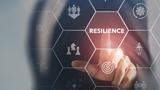 Hand pointing to the word "Resilience" on a projected screen of business concepts, photo by Parradee/Adobe Stock.