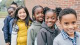 A group of six children of different ethnicities stand in a row, looking towards the camera. Photo by kate_sept2004 / Getty Images