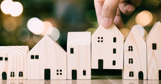House-shaped wooden blocks being placed in a row. Photo by Getty Images