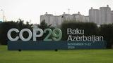 A sign for the COP29 United Nations Climate Change Conference in front of the cityscape in Baku, Azerbaijan, October 31, 2024, photo by Aziz Karimov/Reuters