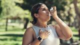 A woman outside using an inhaler for asthma, photo by PeopleImages/Getty Images