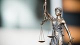 Figurine of Justice in the foreground with a blurred background, photo by ZeynepKaya/Getty Images
