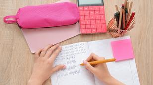 Woman writing math formulas in copybook on wooden table, photo by Pixel-Shot/Adobe Stock
