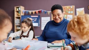 Smiling mature teacher of nursery school looking at one of learners, photo by Seventyfour/Adobe Stock