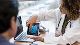 A doctor explains a brain scan to a patient with a tablet, photo by SDI Productions/Getty Images