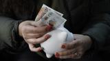 Hands of a woman holding a piggy bank and putting a ten-pound note into it, photo by FJZEA/Getty Images