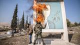 A man burns a picture of former Syrian president Bashar al-Assad close to Syria's border with Lebanon, December 10, 2024, photo by Sally Hayden/SOPA Images via Reuters