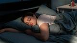 Young woman sleeping in bed, photo by Andrii Lysenko/Getty Images