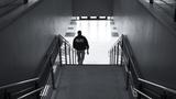 A black and white photo of a police officer in an empty building walking down a flight of stairs, photo by DonTavo/Getty Images