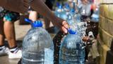 Residents in Cape Town South Africa collect natural spring water with plastic water bottles at Newlands natural spring during the Day Zero water crisis, photo by Mark/Adobe Stock