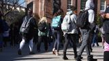 Students wearing backpacks seen from behind as they walk towards a school building. Photo by Sharkshock / Adobe Stock