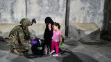 A U.S. paratrooper helps a woman and child evacuating from Afghanistan in August 2021, photo by U.S. Central Command Public Affairs