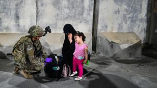A U.S. paratrooper helps a woman and child evacuating from Afghanistan in August 2021, photo by U.S. Central Command Public Affairs