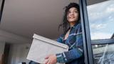 Young Afro-Latina woman holding a fabric box and looking out a window, photo by Mario Arango/Getty Images