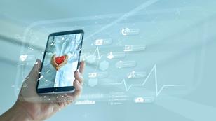 Hand holding a smartphone displaying a medical professional holding a heart, with medical icons emanating out of the phone, photo by ipopba/Getty Images