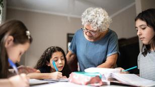 Grandmother helps granddaughters with homework at a table, photo by FG Trade/Getty Images
