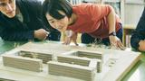 Architecture students looking at a model of buildings, photo by D76MasahiroIKEDA/Getty Images
