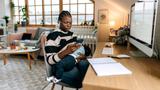 Black mother breastfeeding while looking at her phone, photo by Pekic/Getty Images