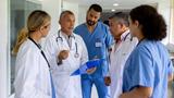 Group of doctors and medical staff talking in a hospital corridor, photo by andresr/Getty Images
