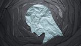 Paper collage of a light blue head looking downward, on top of concentric black frames, photo by tadamichi/Getty Images